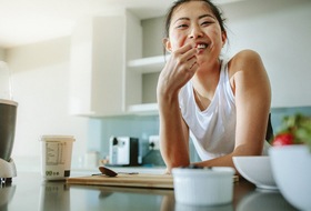 a person leaning on a kitchen counter and eating