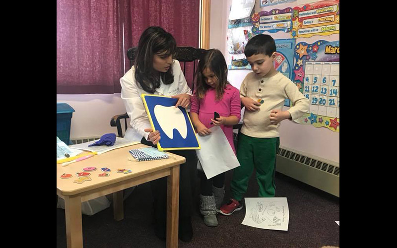 Dr. Phadnis teaching two young patients about teeth