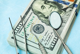 Dental tools lying on a stack of dollar bills