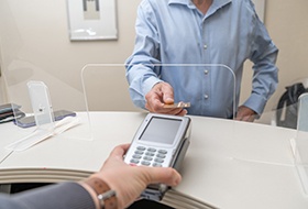 A man using a credit card to pay the cost of dental care