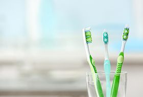 Three toothbrushes sitting in a transparent cup