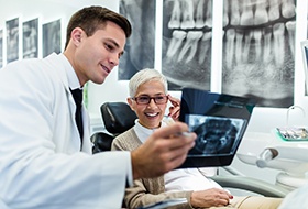 Dentist reviewing X-ray with smiling patient