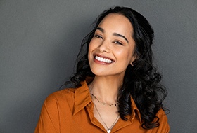 Woman in orange shirt with dark hair smiling