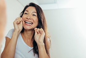 Patient smiling while flossing her teeth