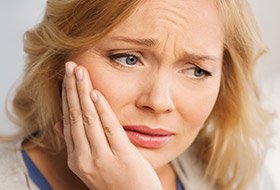 Woman holding cheek in pain