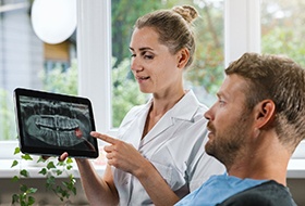 Dentist showing man his X-ray with wisdom tooth highlighted red