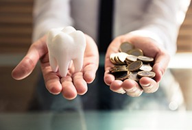 a person holding coins and a model tooth
