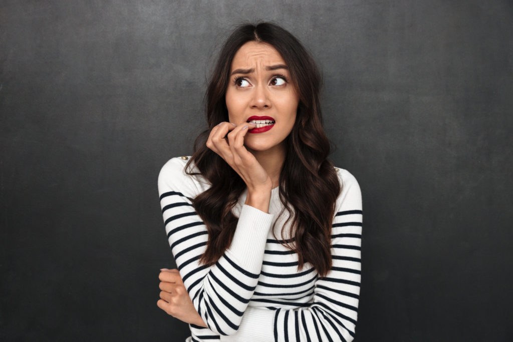 Woman demonstrates bad dental habits by chewing on a fingernail.