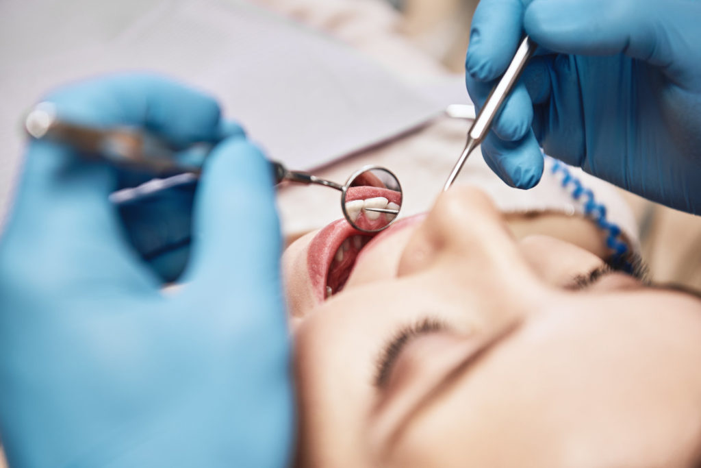 Dentist inspects a patient’s mouth.