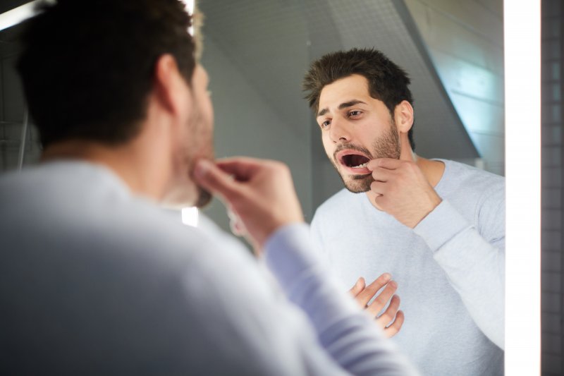 Man checking tooth in hotel mirror