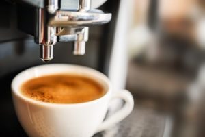 a white mug sitting under an espresso machine