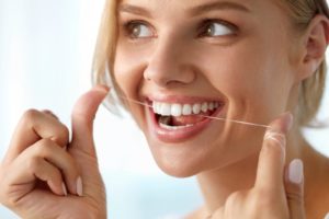 young woman flossing teeth