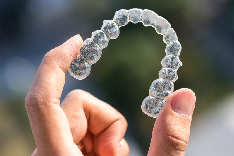 young woman holding her invisalign aligner