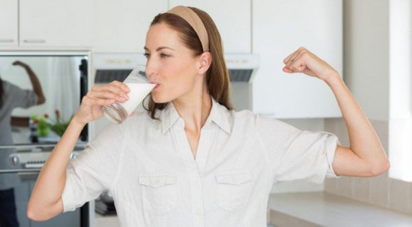 person drinking a glass of milk that’s full of calcium